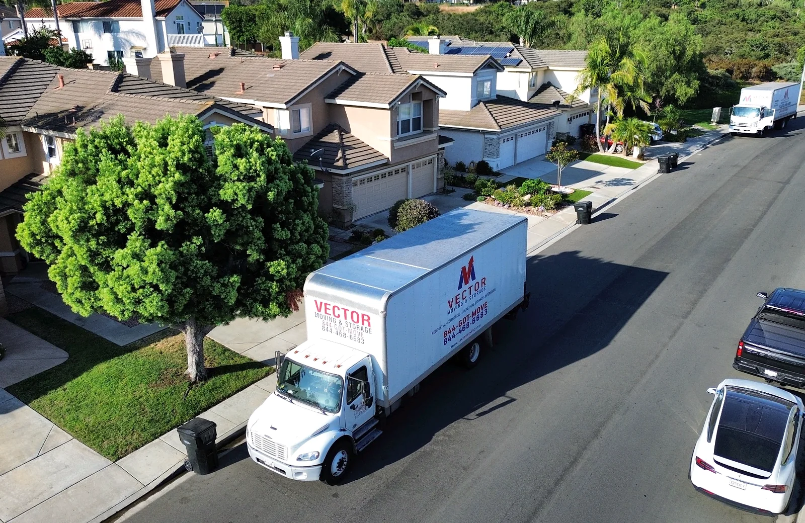 Vector Moving and Storage trucks in a residential San Diego neighborhood