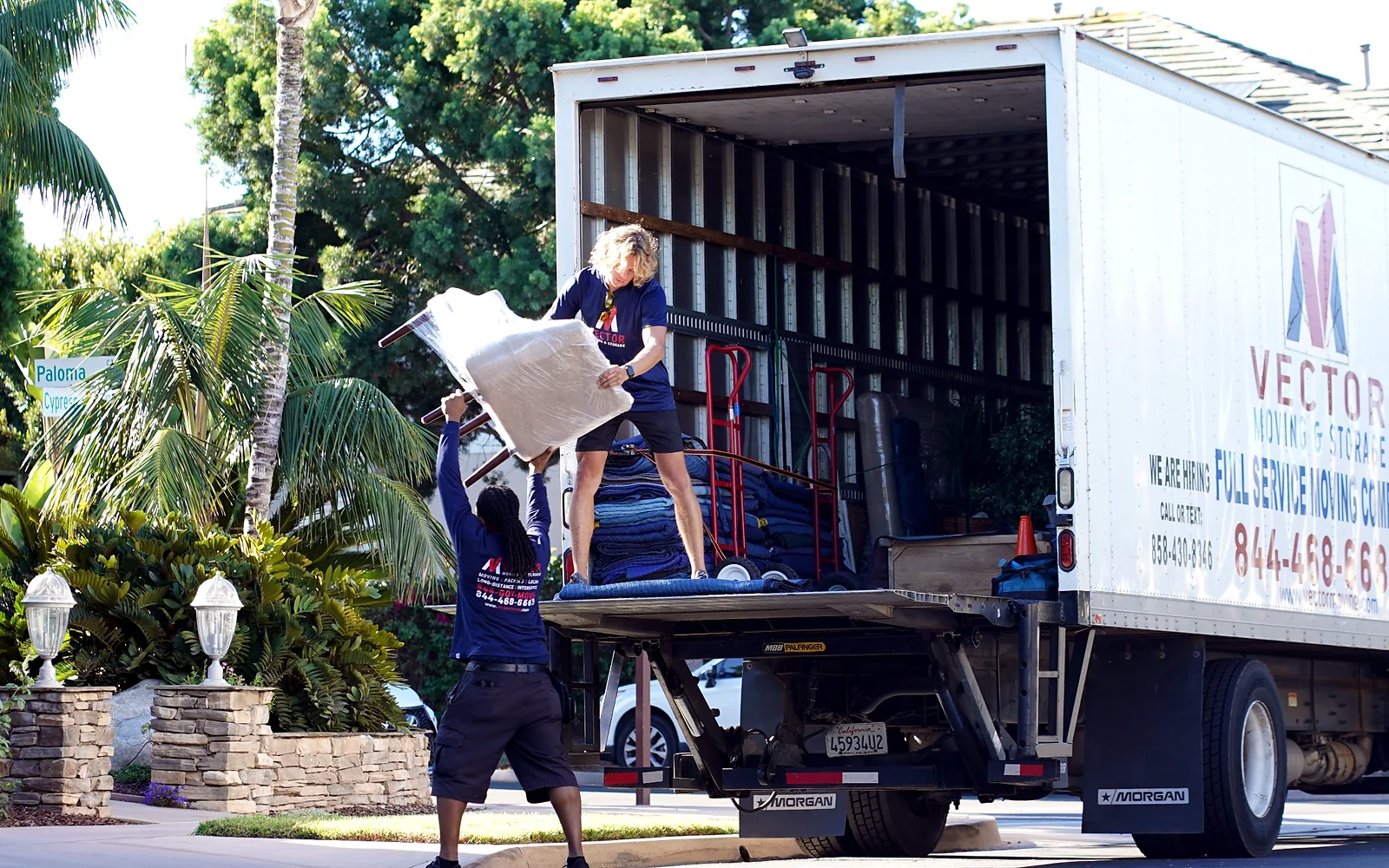 Vector movers loading protected furniture into a branded moving truck