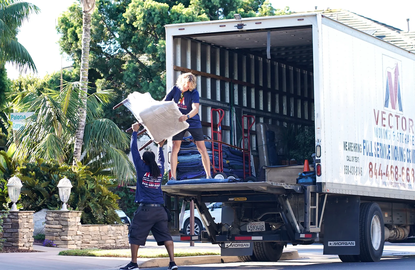 Vector movers loading protected household furniture into a moving truck