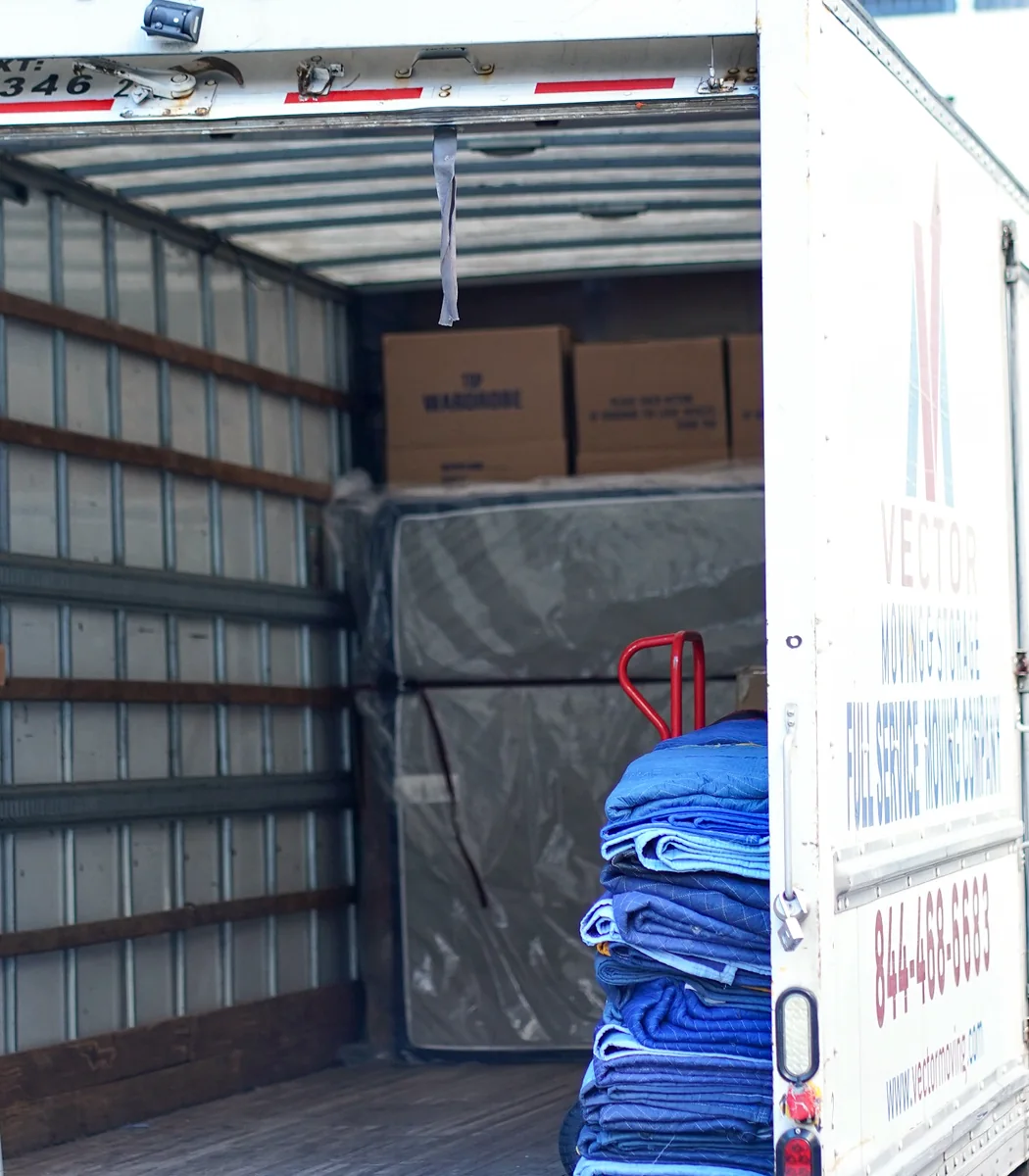 Moving blankets, wardrobe boxes, dollies and protected furniture inside a Vector truck