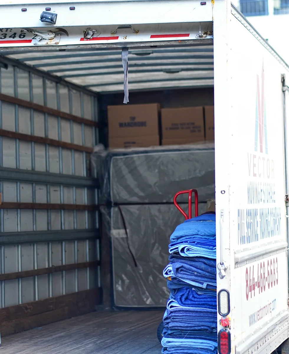 Moving blankets, boxes, dollies and protected furniture inside a Vector truck