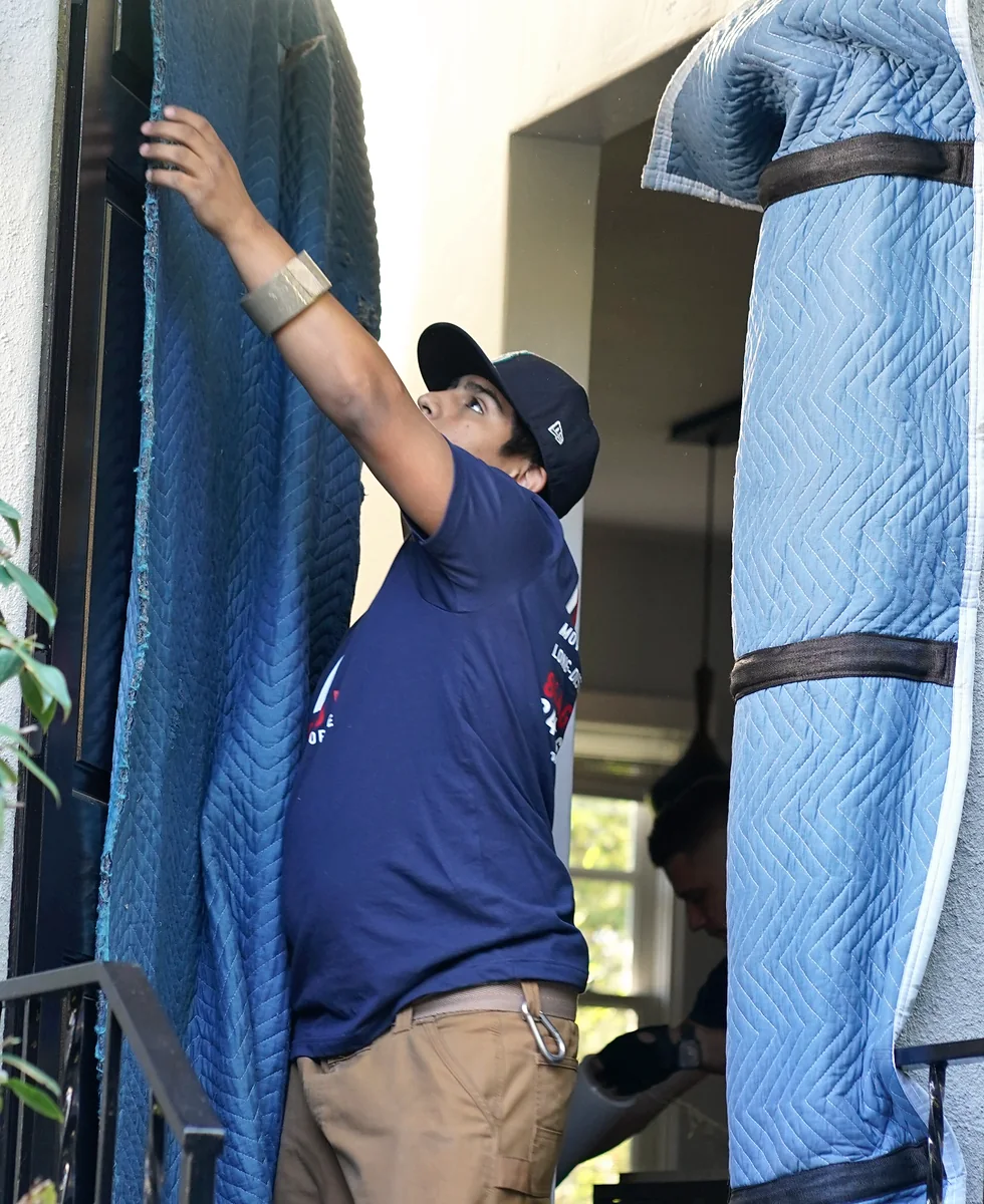Vector mover installing padded doorway protection before moving furniture