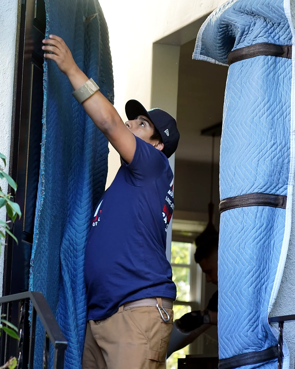Vector mover installing padded doorway protection before moving furniture