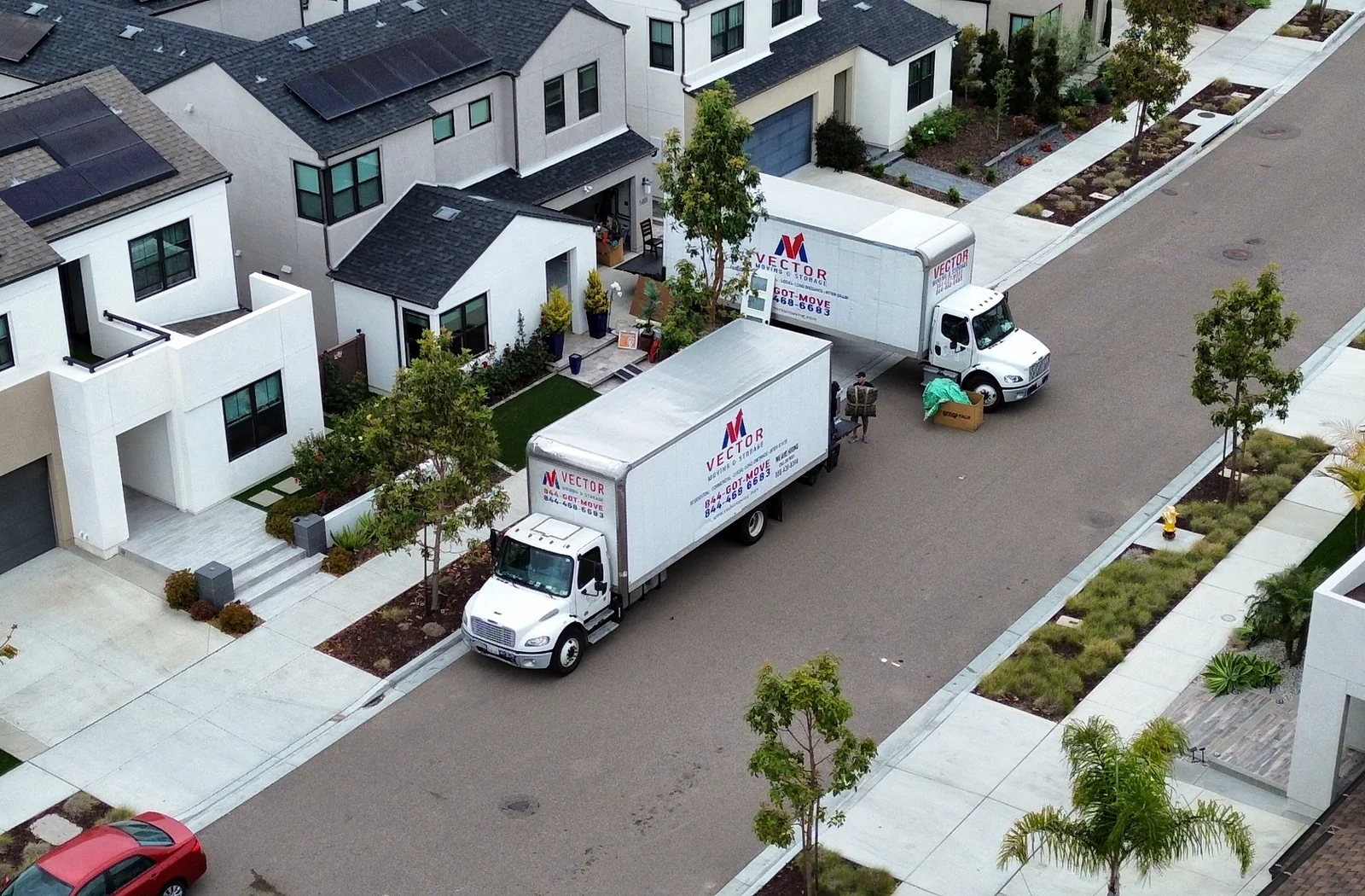 Two Vector Moving and Storage trucks in a modern residential community