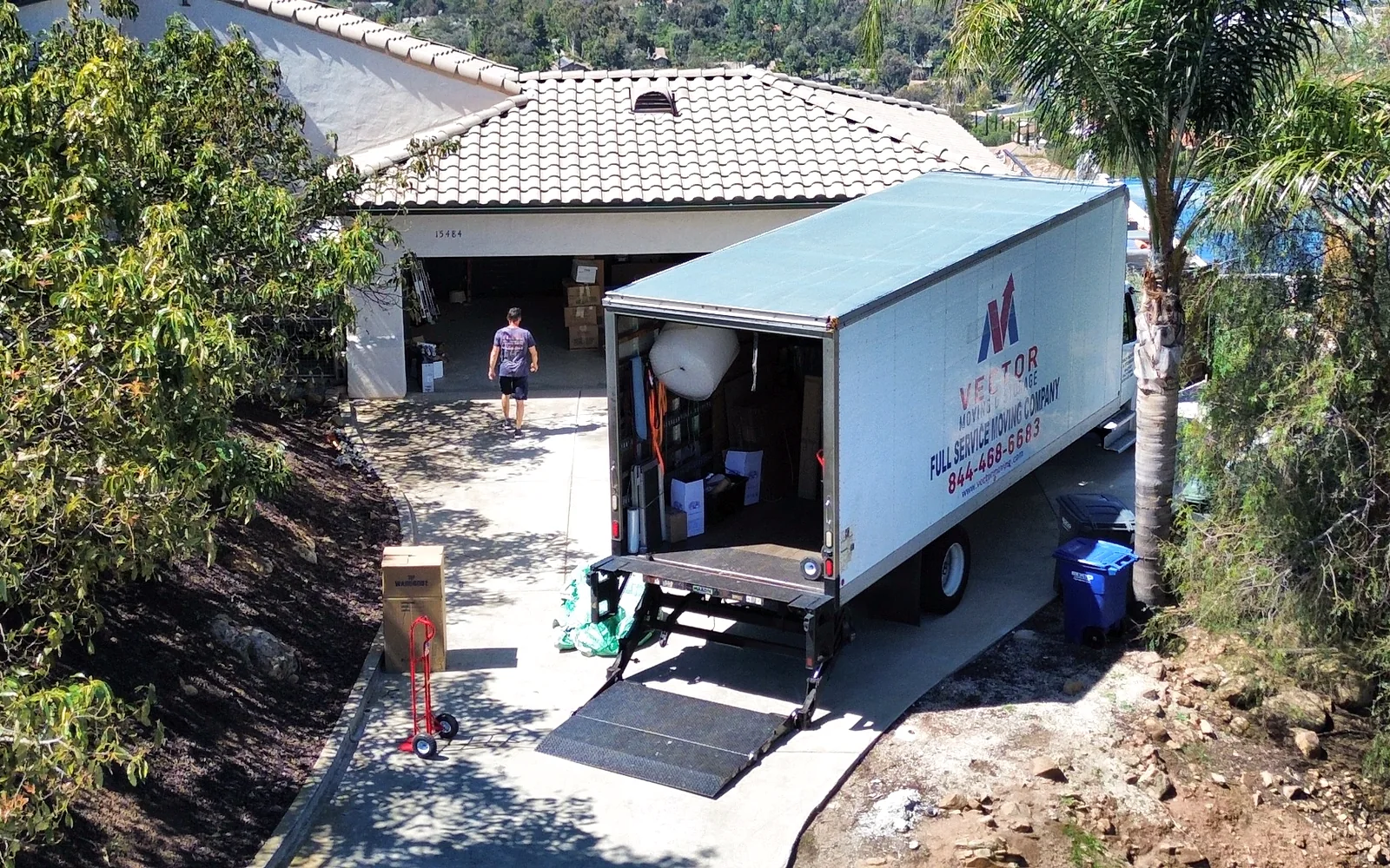 Vector moving truck positioned on a sloped residential driveway