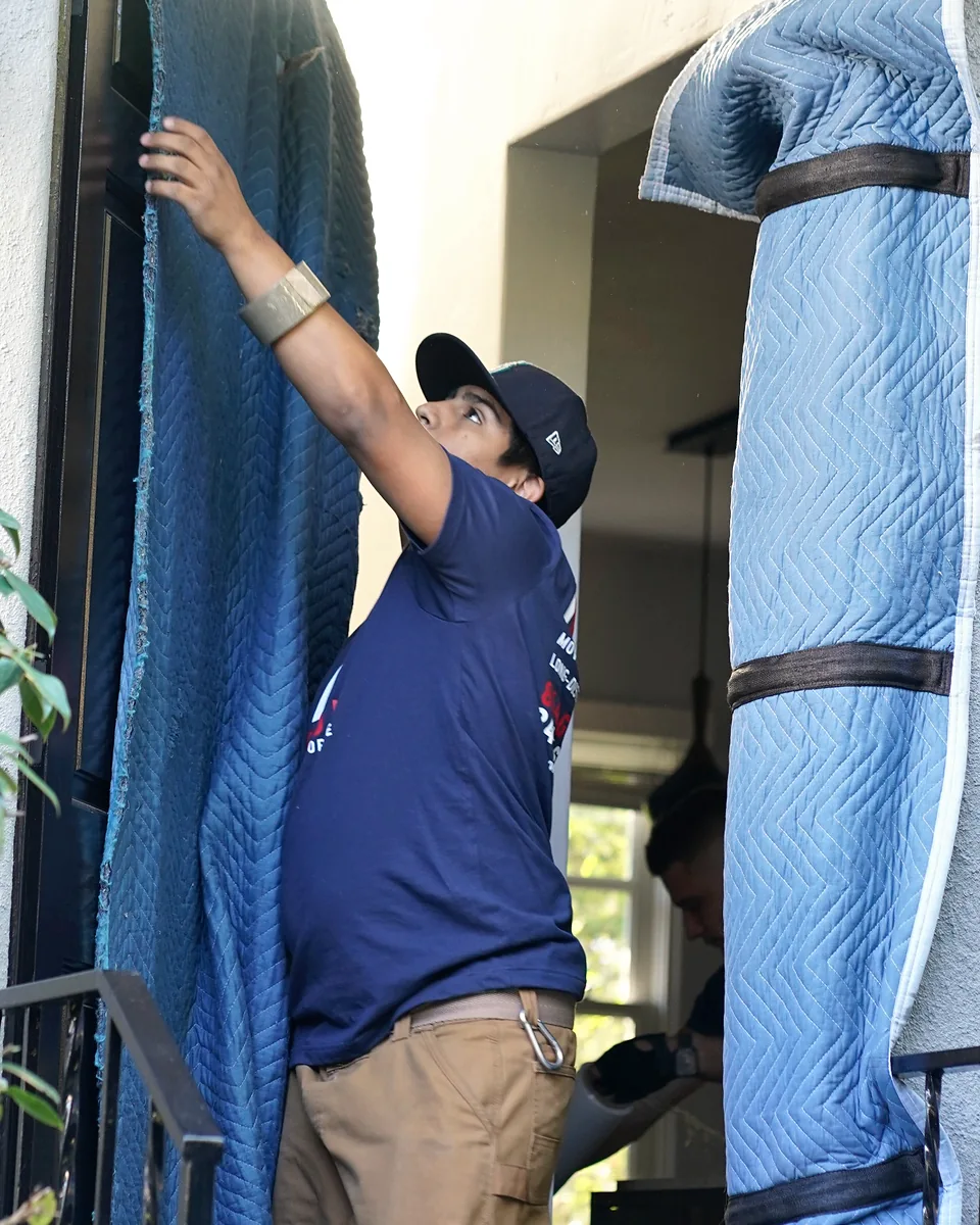 Vector mover installing padded doorway protection before a move