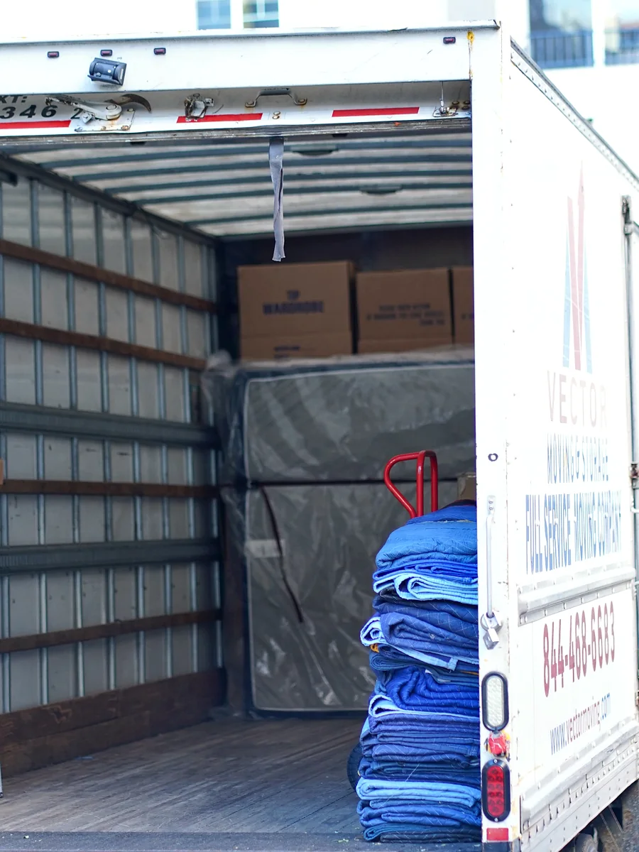 Moving blankets boxes dollies and protected office furniture inside a Vector moving truck