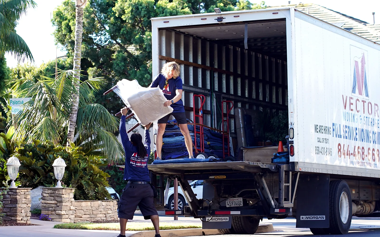 Vector movers loading protected household furniture into a moving truck