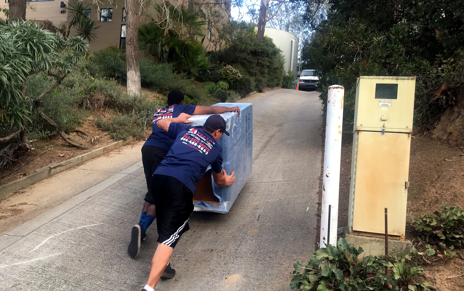 Vector movers handling protected furniture on a sloped residential access route