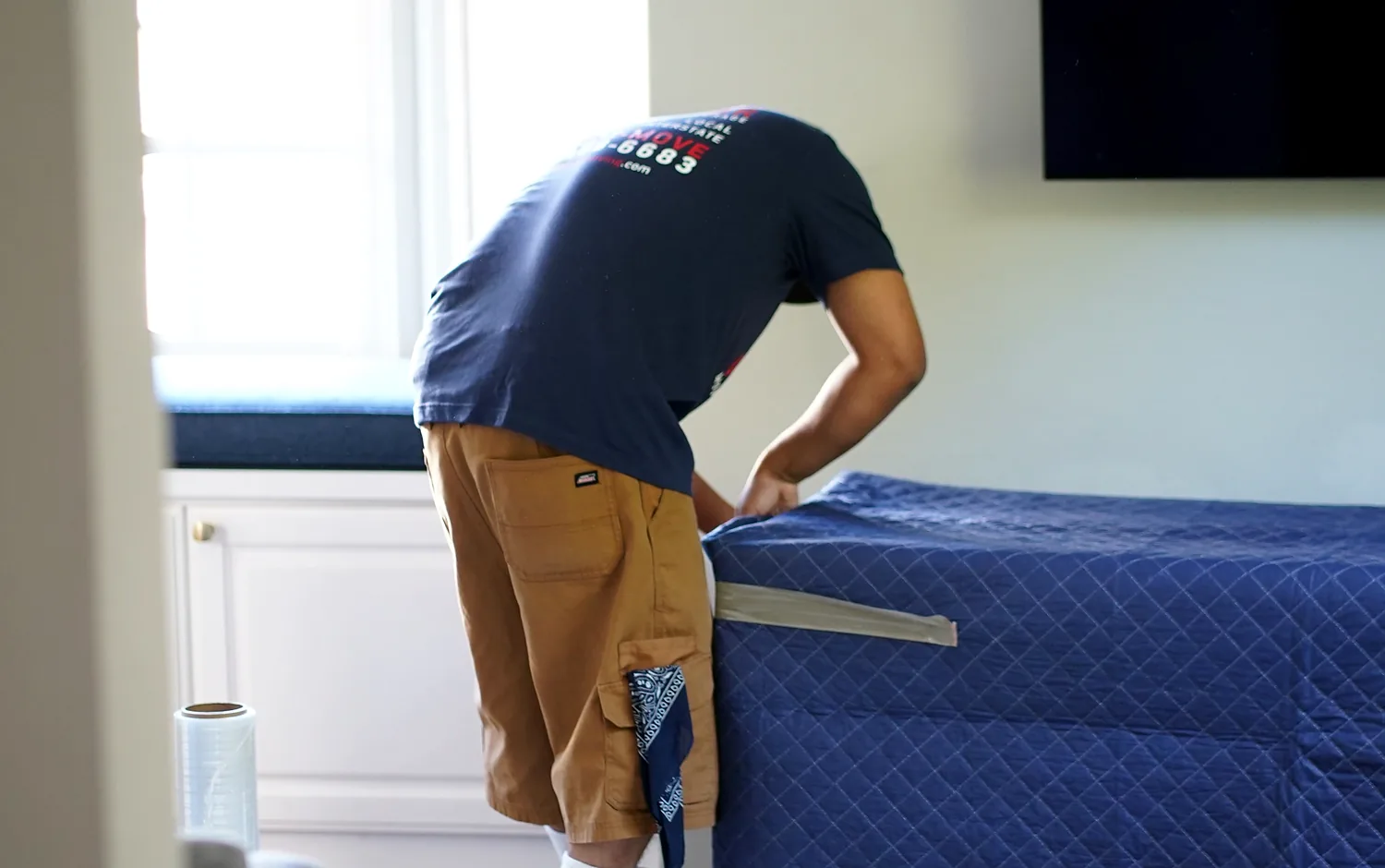 Vector mover securing a professional moving blanket around a furniture piece