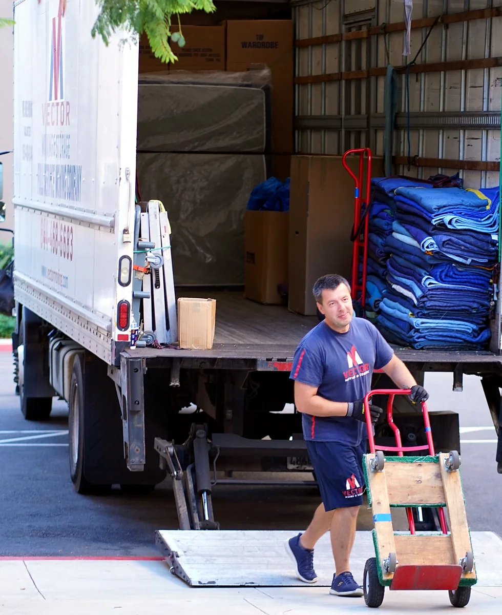 Vector mover with commercial moving equipment beside a loaded truck