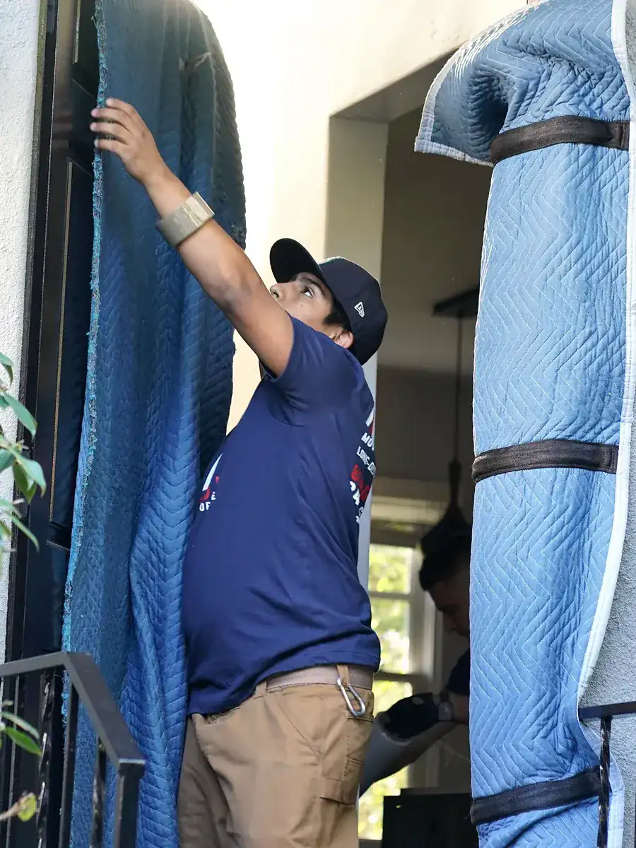 Vector mover installing padded doorway protection before moving furniture