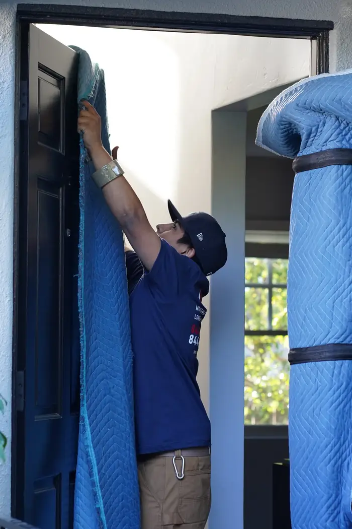 Vector mover installing padded doorway protection before carrying furniture