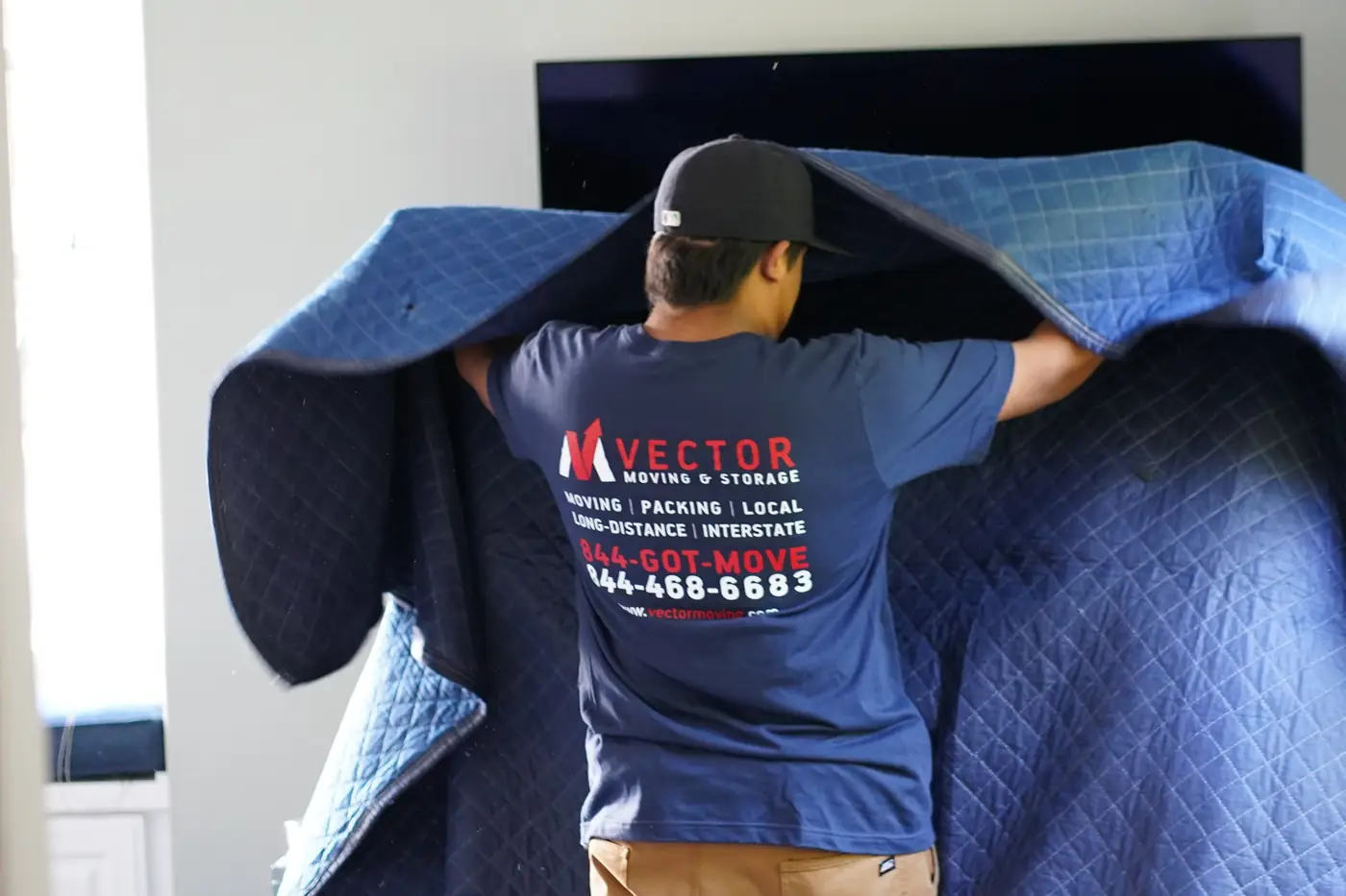 Vector mover preparing furniture with a quilted moving blanket