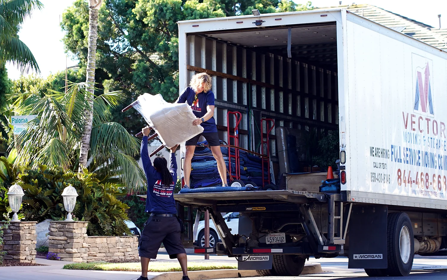 Vector movers transferring protected household furniture at a moving truck