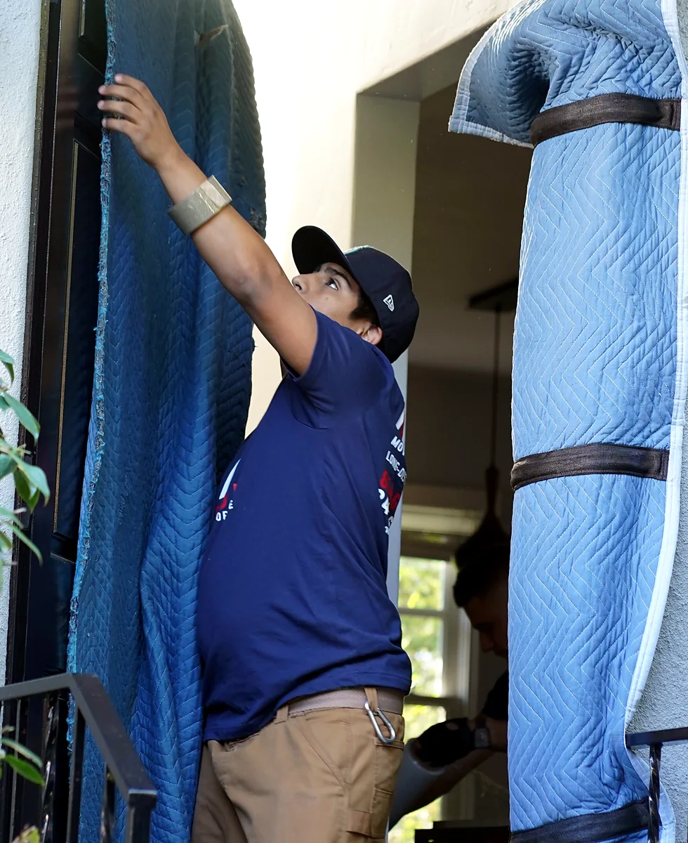 Vector mover installing padded doorway protection before moving furniture