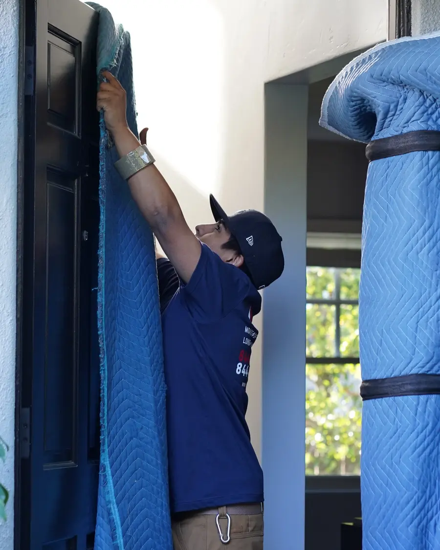 Vector mover installing protective moving blankets around a doorway