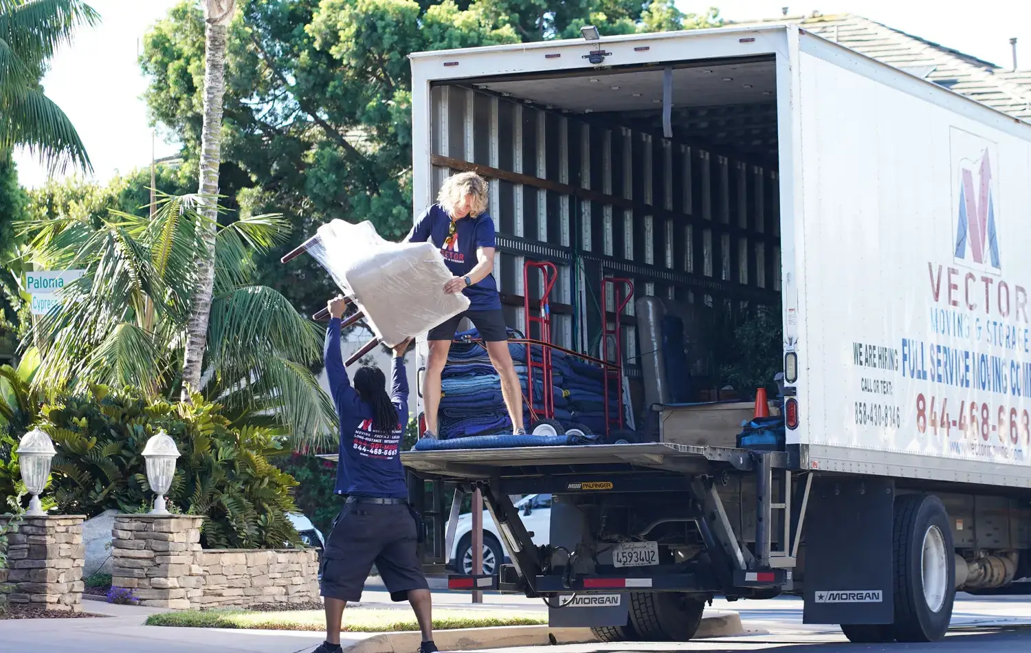 Vector movers loading a wrapped chair into a company truck