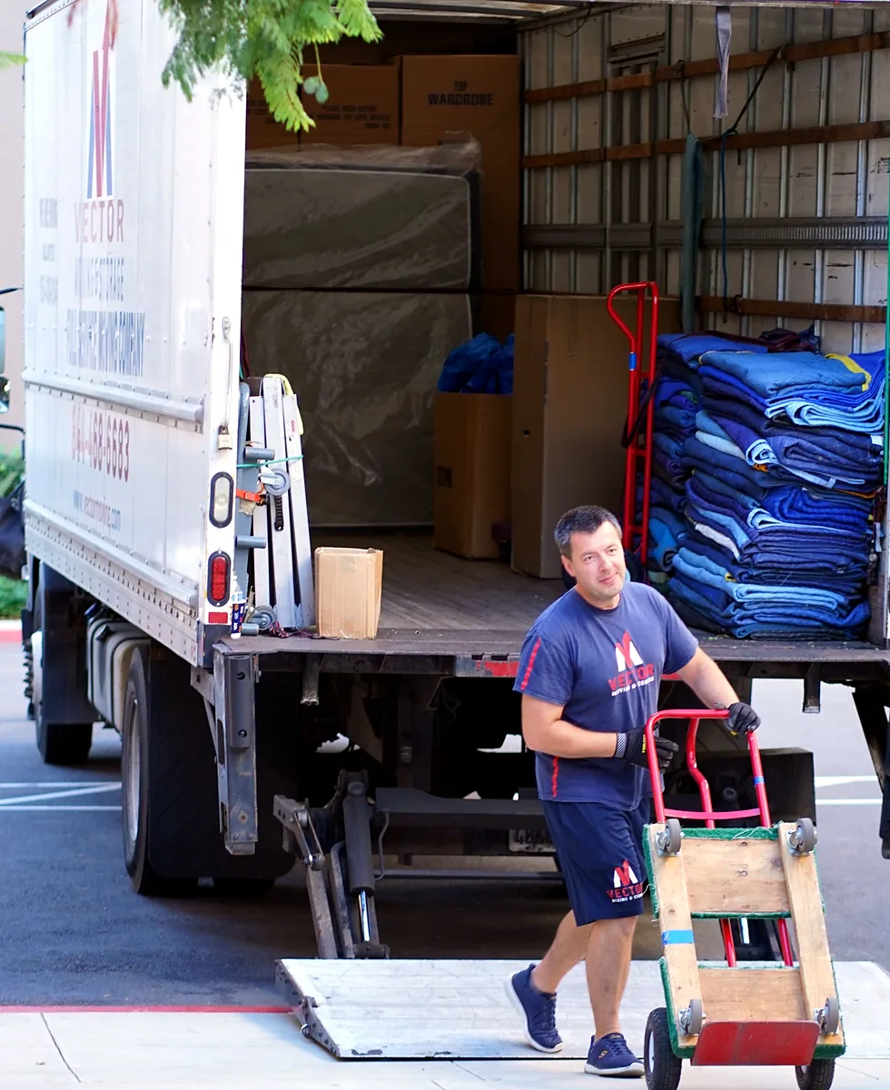 Vector mover with a hand truck beside a loaded moving truck