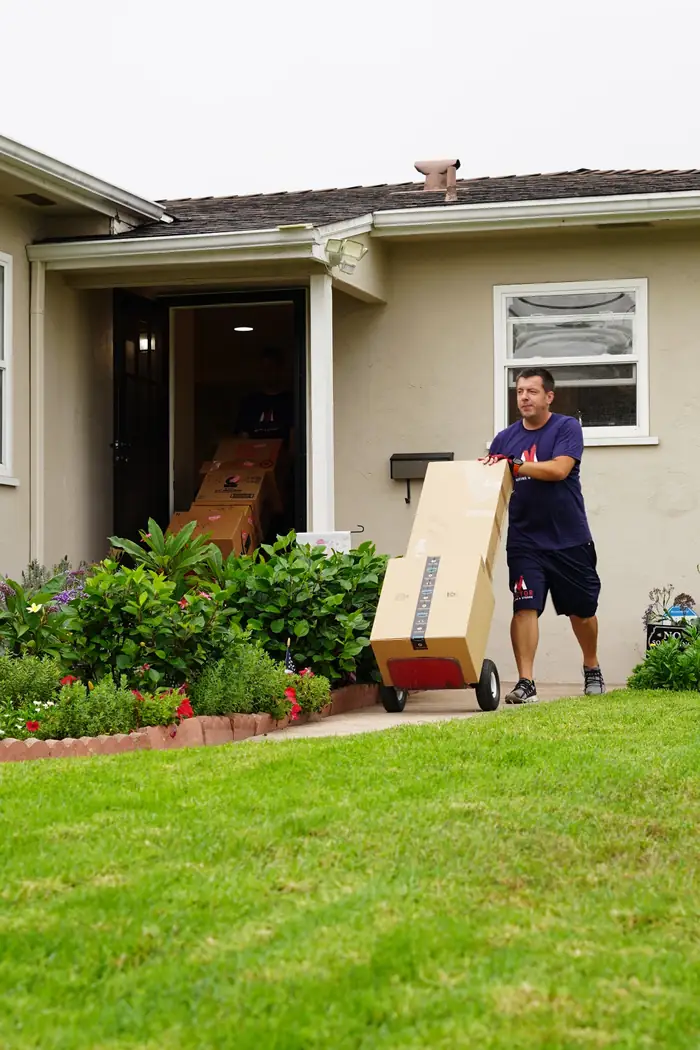 Vector movers working beside an open branded moving truck at a residence