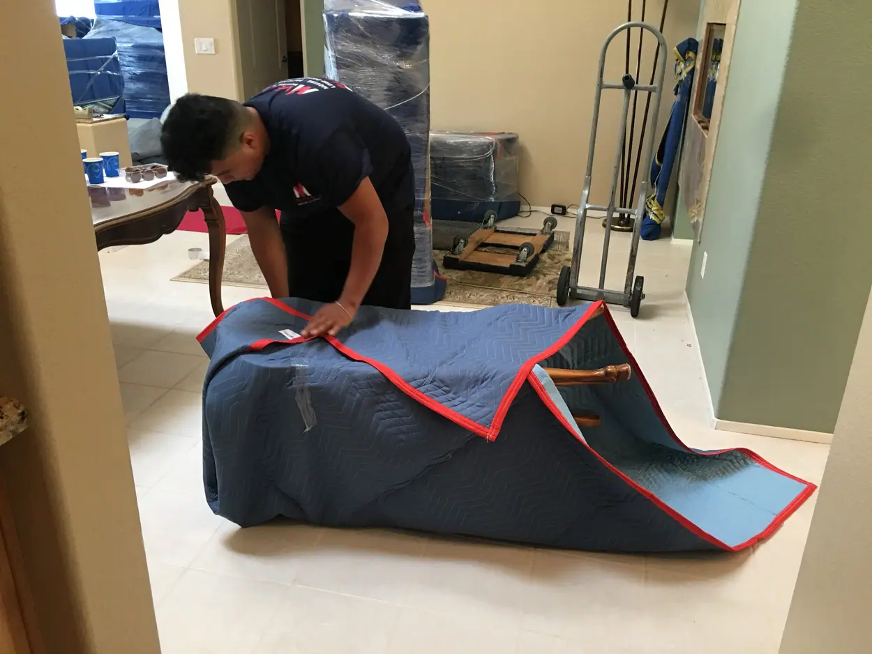 Vector mover wrapping household furniture with a quilted moving blanket