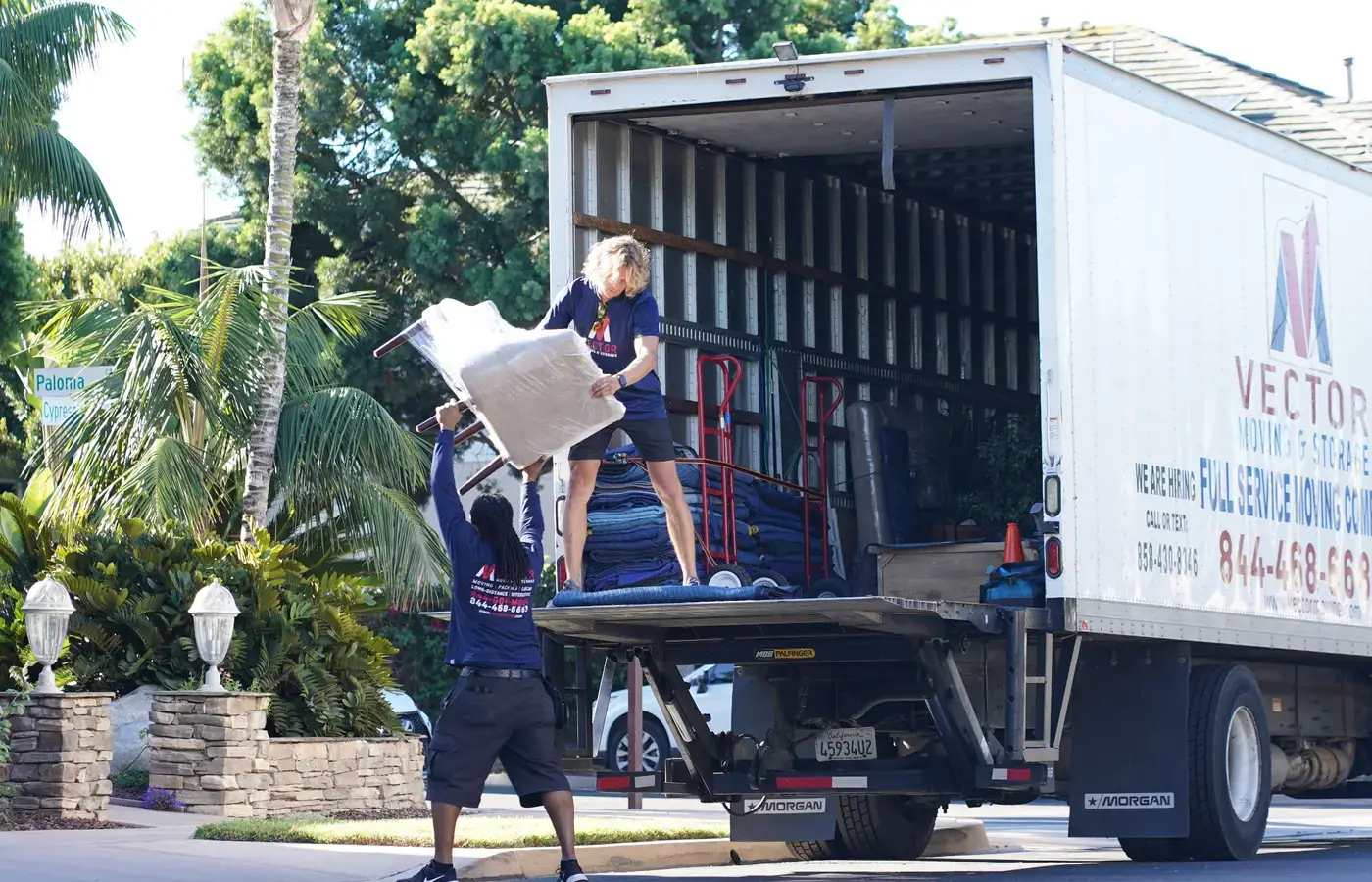Vector moving crew loading protected furniture into a prepared moving truck