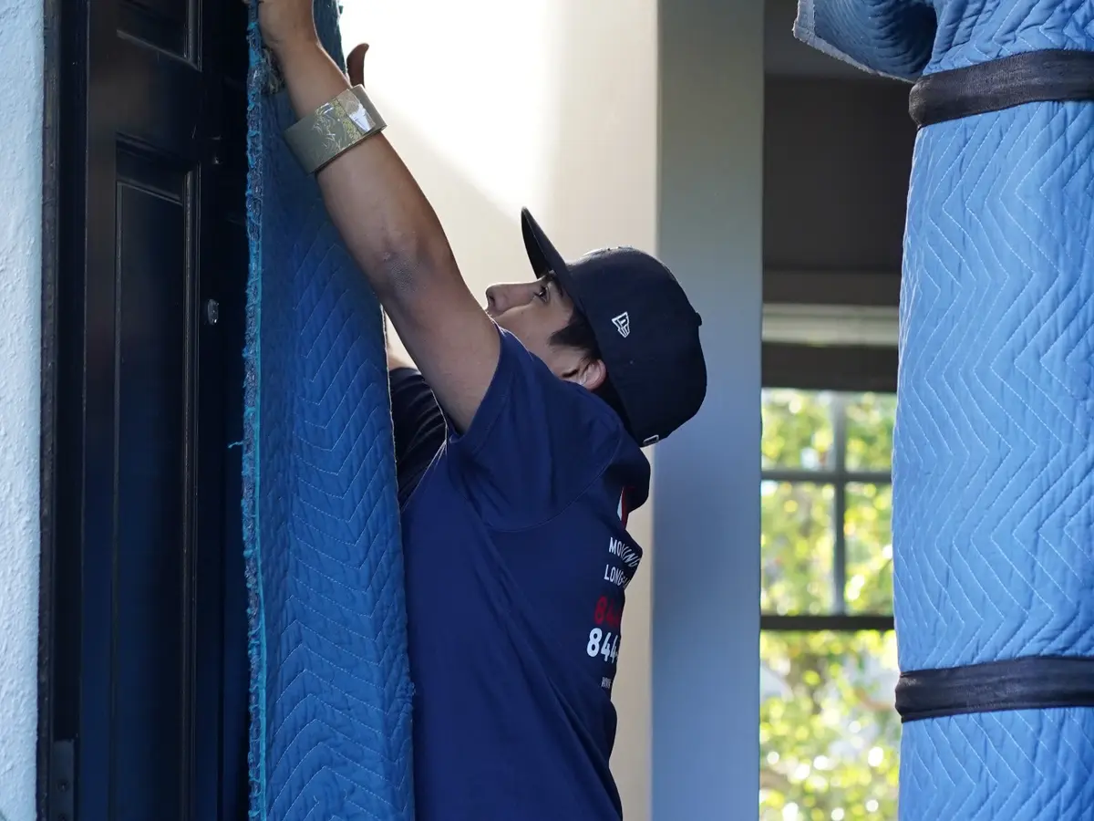 Vector mover installing protective padding at a residential doorway