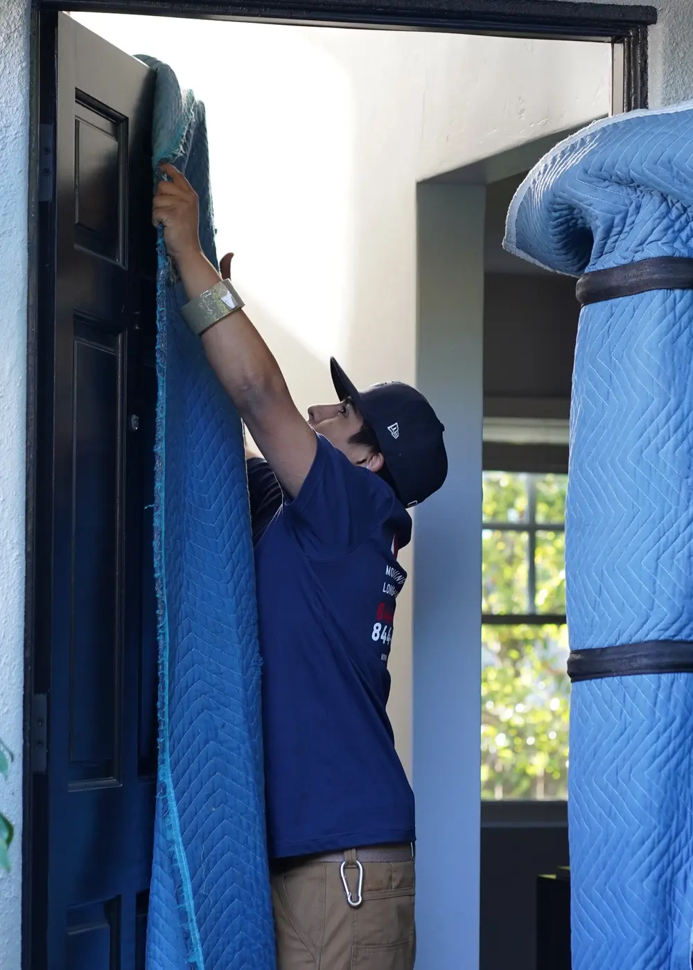 Real Vector mover installing protective moving blankets at a residential doorway