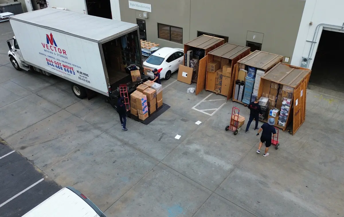 Vector crew transferring boxed inventory between storage vaults and a moving truck